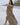 Image shows brunette female model on beach. Model is wearing a brown maxi dress.