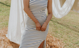 Brunette female model is wearing a white and blue striped midi dress.