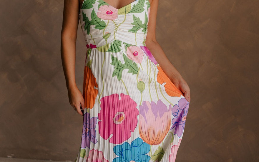 Blonde female model is wearing a pleated multi-color floral maxi dress