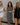 image shows 3 women with arms interlinked. Left woman is wearing a white romper, middle woman is wearing a striped midi dress, and the right woman is wearing a black romper.