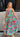 Full body front view of female model wearing a colorful printed maxi dress.