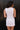 Back view of model wearing the Harper Off White Sleeveless Mini Dress which features white denim fabric, mini length, scooped slit, round neckline with scoop detail, sleeveless and monochrome back zipper with hook closure.