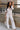 Full body view of model wearing the Bella Ivory Plunge Neckline Flare Jumpsuit which features white knit fabric, plunge neckline, short flare sleeves, open back, monochrome back zipper with hook closure and flare pant legs.