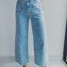 Front view of model wearing the Ceros: Florence Light Wash Wide Leg Jeans which features light denim wash fabric, two front pockets, two back pockets, front zipper with button closure, belt loops, super high waisted, wide cropped flares and distressed hem