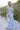 Full body front view of female model wearing the Camila White & Blue Floral Ruffle Maxi Dress which features Blue and White Floral Print, Maxi Skirt, Slit Detail, White Lining, Smocked Upper and Ruffle Straps