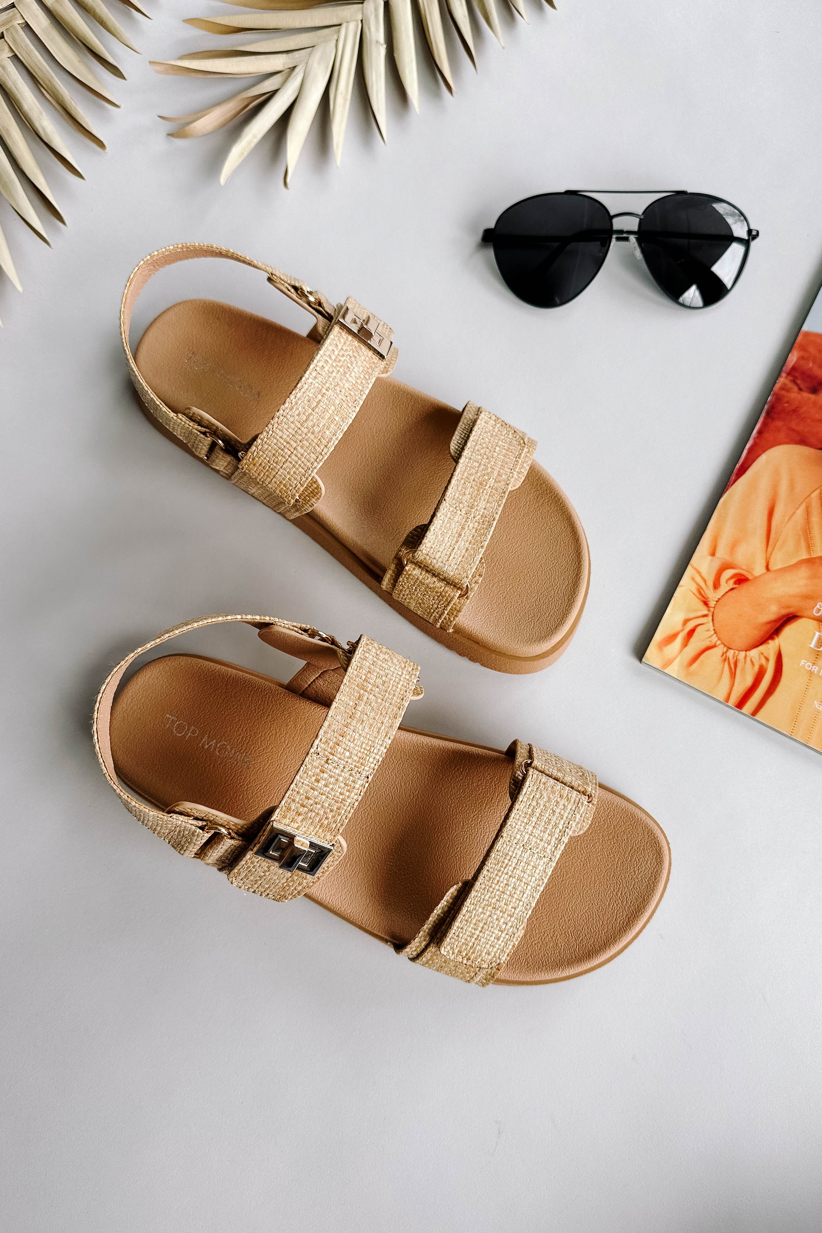 Ariel view of the Lyon Sandal in Beige Raffia which features natural raffia fabric, two adjustable velcro straps, adjustable back strap and round toe.