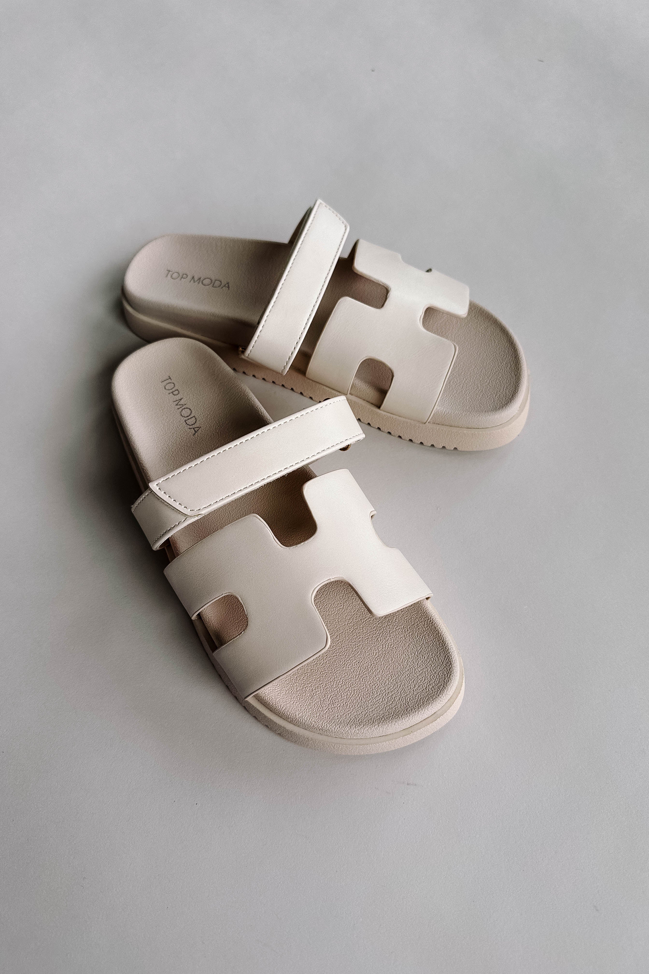 Front view of the Jade Strap Sandal in Ivory which features ivory leather fabric, slide-on style, H-shaped strap, adjustable velcro strap and round toe.