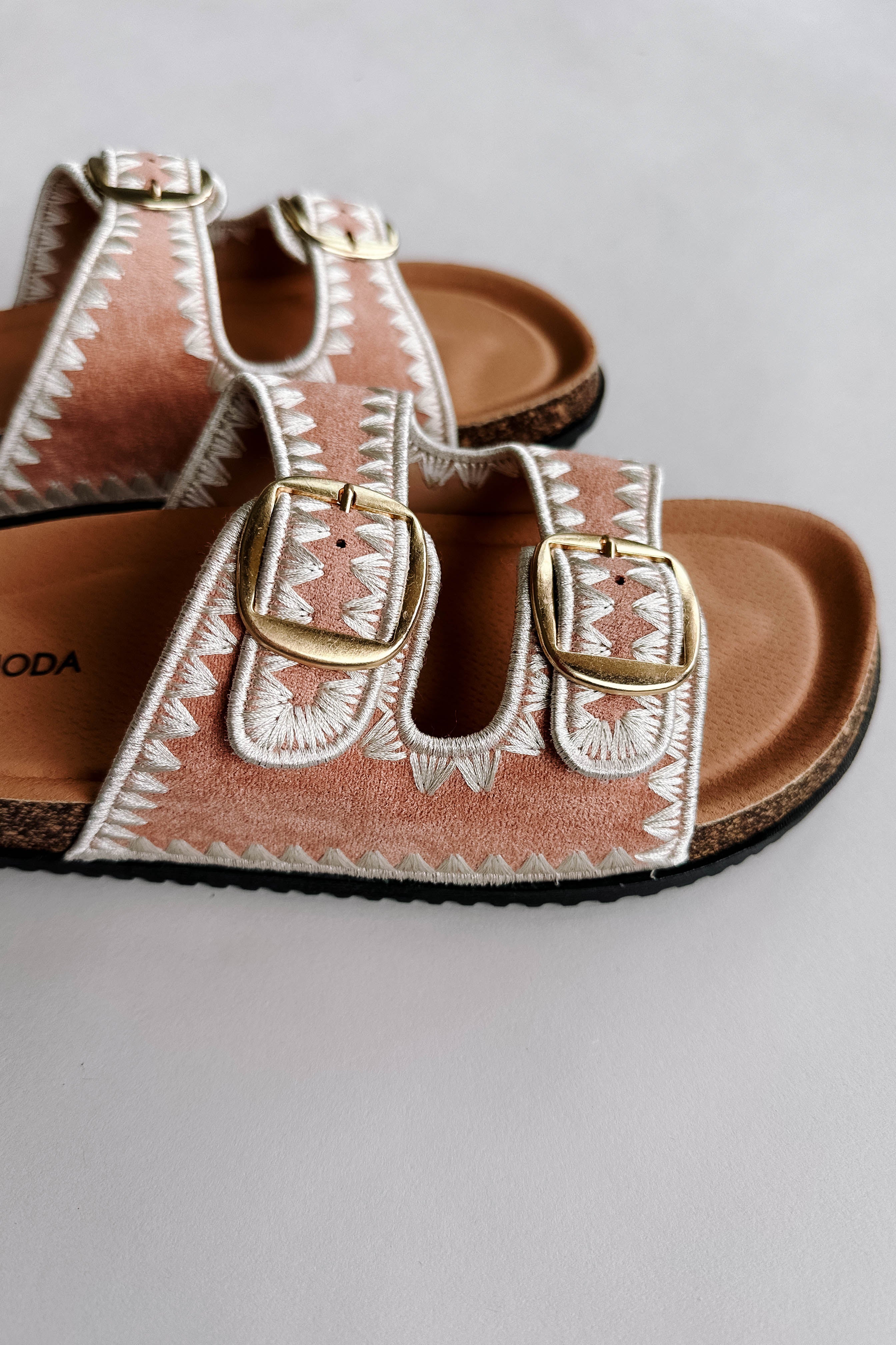 Close up side view of the Luca Sandal in Blush which features blush fabric, cream geometric trim design, two adjustable straps, gold buckles and slide-on style.