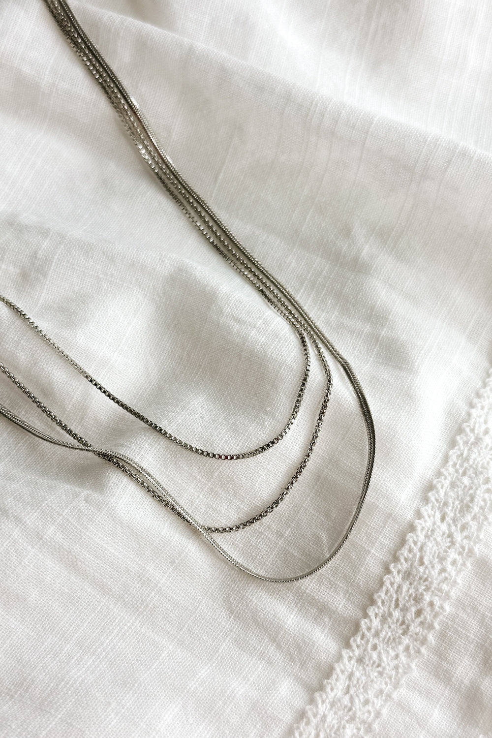 Close up view of the Camila Silver Triple Layered Chain Necklace which features silver triple layer chain necklace