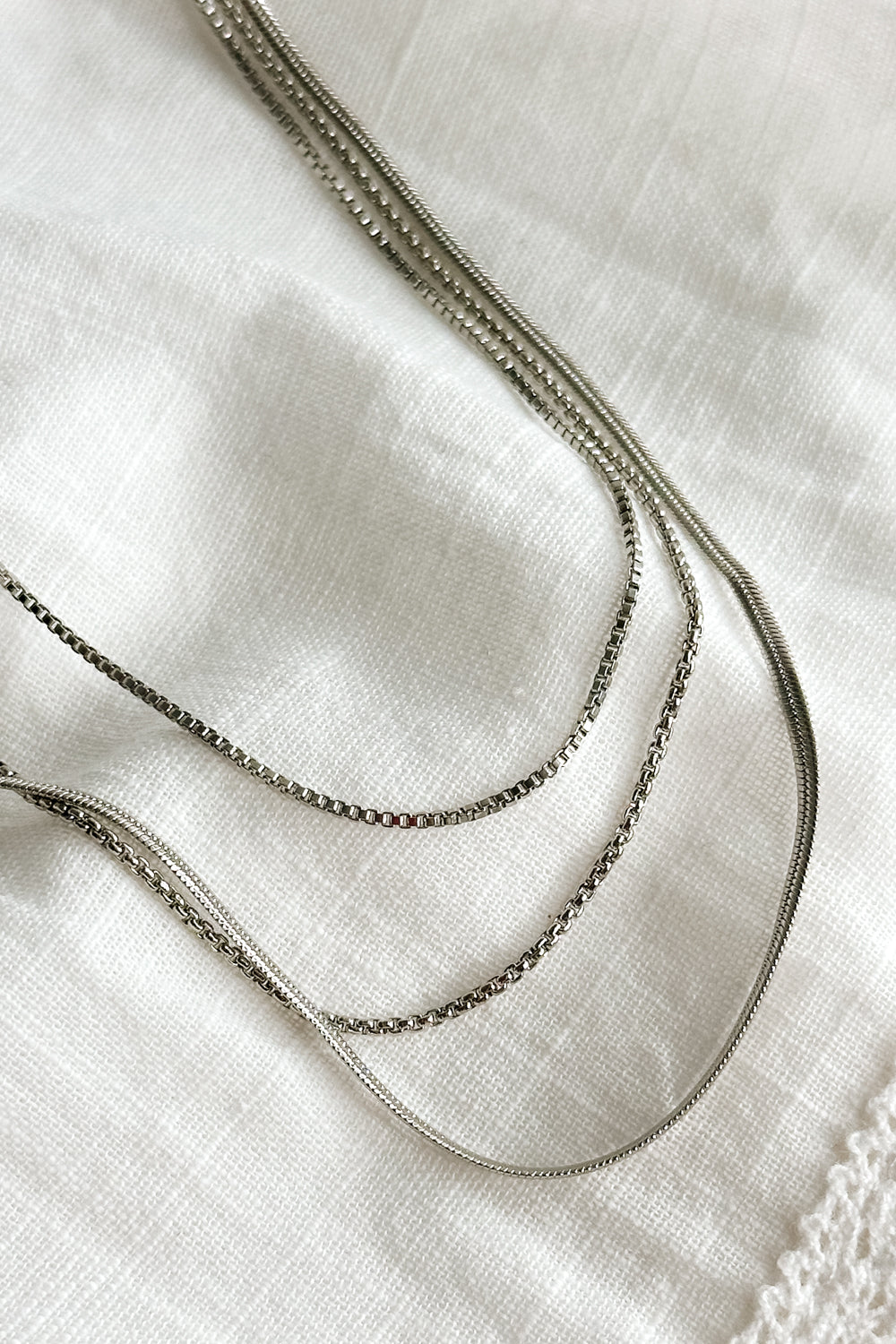 Close up view of the Camila Silver Triple Layered Chain Necklace which features silver triple layer chain necklace