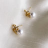Flat lay close up view of pearl and Bow Earrings features pearls with gold and clear rhinestones bows attached.