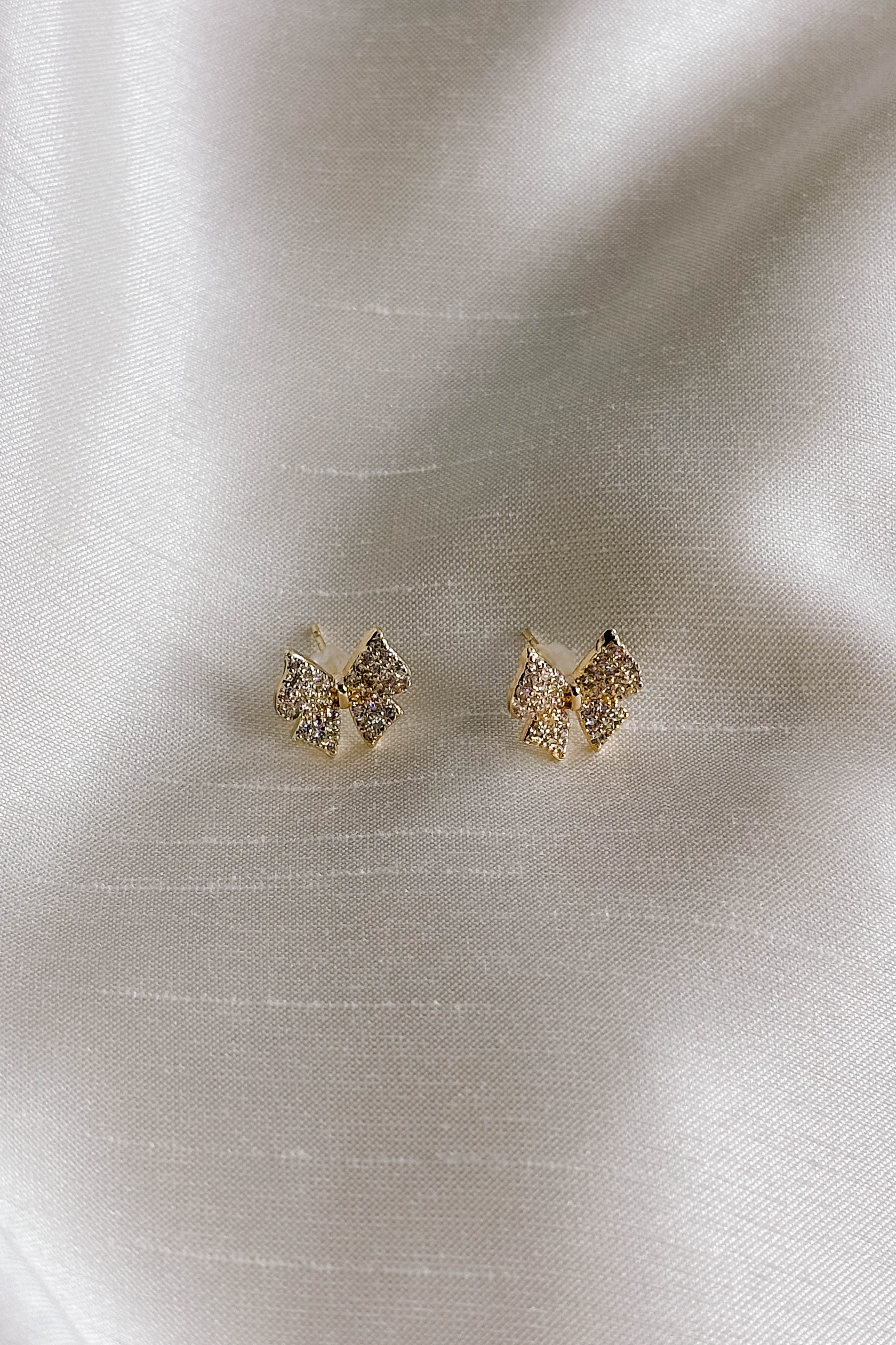 Flat lay picture of Blaire Bow Stud Earrings features mini gold bow shaped studs.