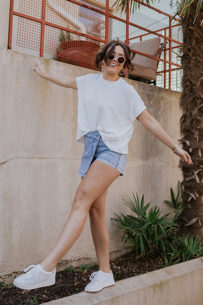 Full body view of model wearing the Everly Off White Ribbed Short Sleeve Top which features white ribbed fabric, a round neckline, and short dolman sleeves with ribbed cuff details.