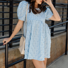Front view of model wearing the Amelia Light Blue Short Puff Sleeve BabyDoll Dress which features light blue textured fabric, bubble pattern design, mini length, round neckline, short puff sleeves and back button closure.