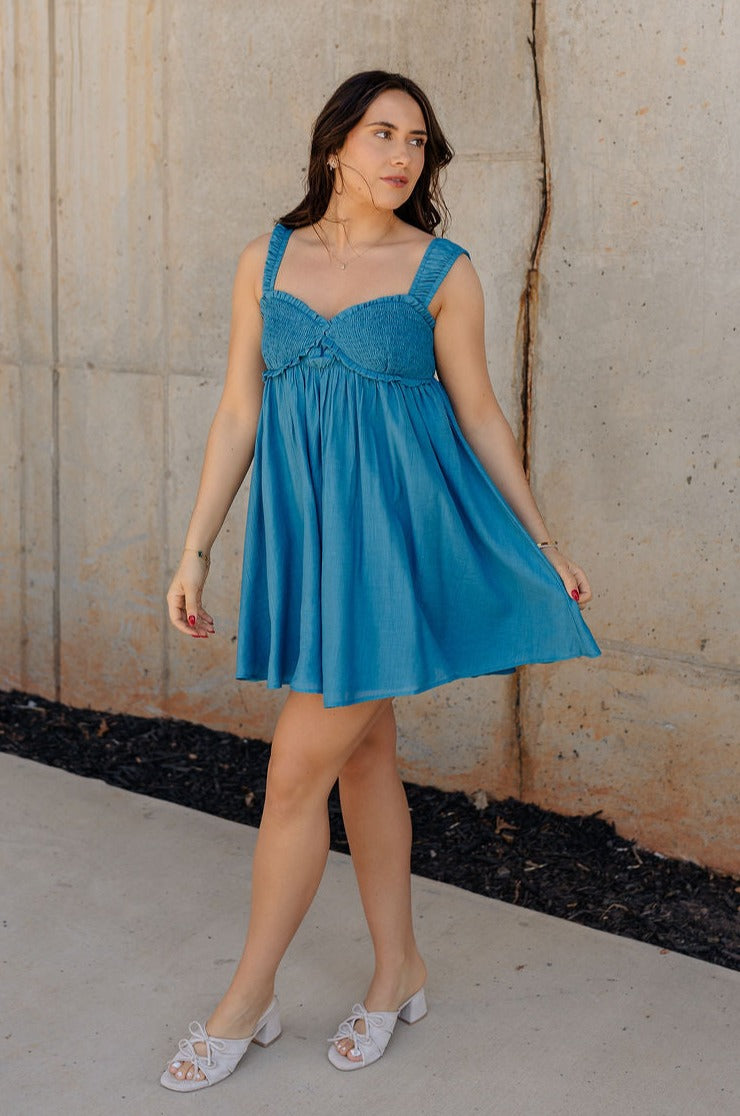Full body view of model wearing the Lucille Dark Turquoise Sleeveless Mini Dress which features dark turquoise fabric, a smocked sweatheart neckline and back, smocked thick straps, and dark turquoise lining.