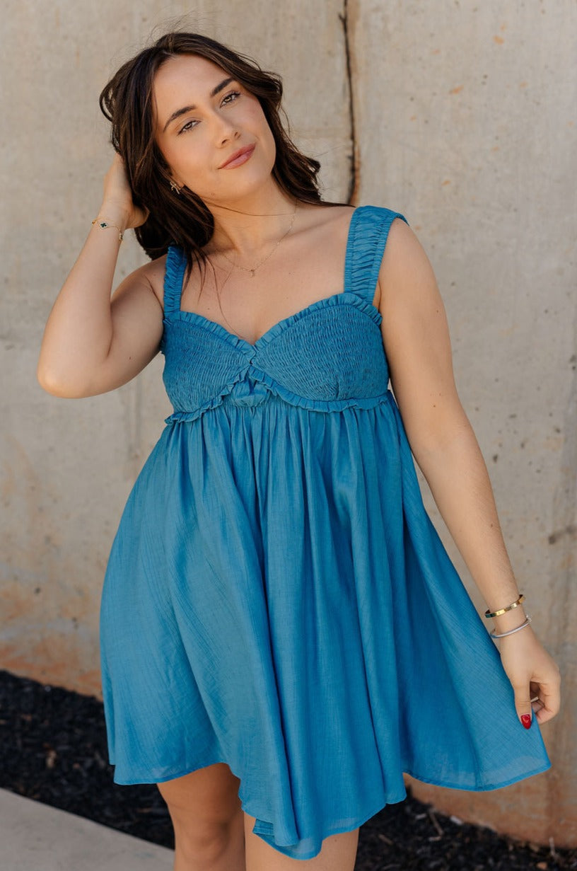 Front view of model wearing the Lucille Dark Turquoise Sleeveless Mini Dress which features dark turquoise fabric, a smocked sweatheart neckline and back, smocked thick straps, and dark turquoise lining.