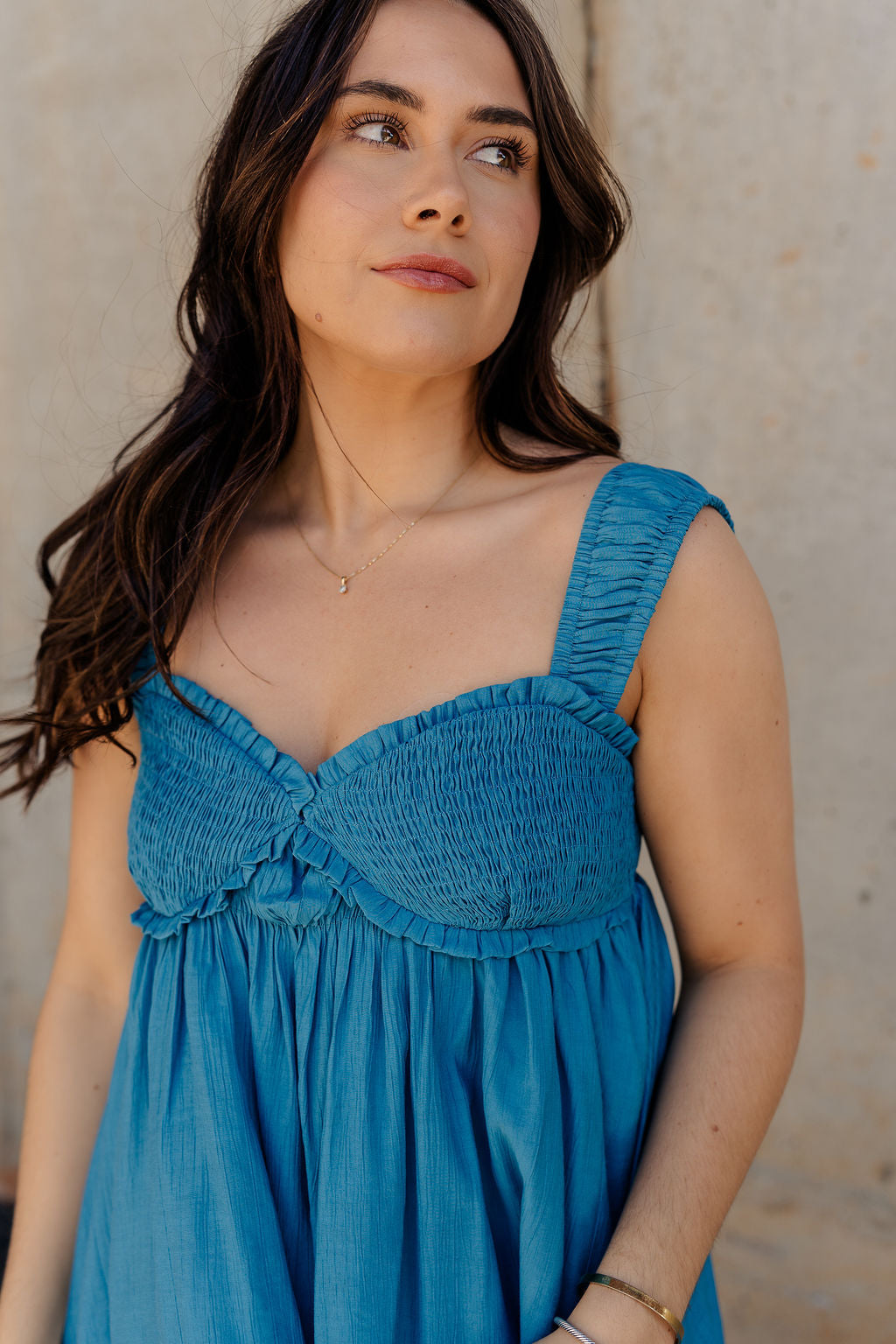 Close up view of model wearing the Lucille Dark Turquoise Sleeveless Mini Dress which features dark turquoise fabric, a smocked sweatheart neckline and back, smocked thick straps, and dark turquoise lining.