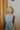 Upper front view of model wearing the blue colored Eleanor Sleeveless Button Front Mini Dress that has cotton fabric, a button-up front with silver buttons, buttoned chest pockets, a collared neckline, and a racerback cut.