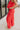 Side view of model wearing the Vada Red Wide Leg Pants that feature red woven fabric, side pockets, an elastic waistband, and flowy wide legs.