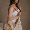 Side view of female model wearing the Amber Natural Braided Purse which features natural tan leather fabric, braided strap, gold zipper and gold hardware details