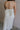 Back view of female model wearing the Rebecca Off White Pearl Bow Midi Dress which featuresCream Sheer Fabric, Midi Length, Cream Lining, Strapless, Pearl Details and Bow Back Detail