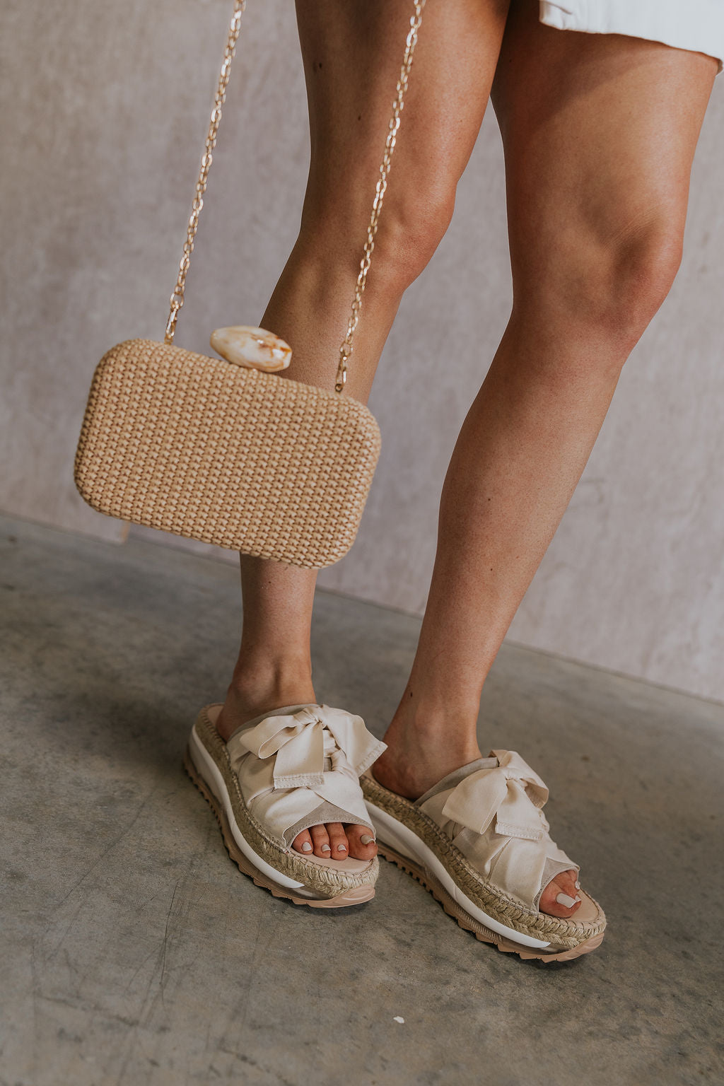 Front side view of female model wearing the Chapmin Sport Sandal which features slip-on style, slingback design, round open toe, natural suede toe strap, triple-stacked platform sole, espadrille detailing, clear midsole, tread outsole, oversized ribbon laces, self-tie slingback strap