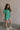 Full body side view of female model wearing the Destiny Ribbed Short Sleeve Top in kelly green which features Ribbed Fabric, Round Neckline and Short Sleeves.
