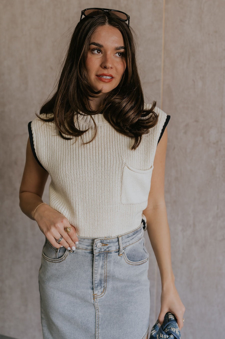 Front view of female model wearing the Vivian Ivory & Navy Knit Sleeveless Sweater which features Cream Cable Knit Fabric, Navy Trim Details, Left Front Chest Pocket, High Neckline and Sleeveless.