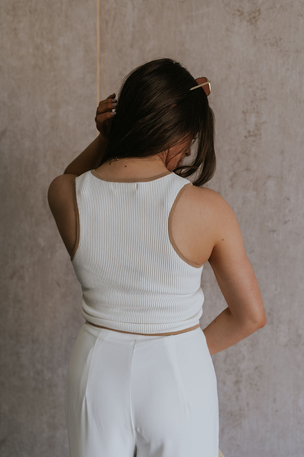 Back view of female model wearing the Sienna Off White & Tan Sleeveless Tank which features White Ribbed Fabric, Tan Trim Details, Round Neckline and Sleeveless