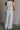 Back view of female model wearing the Sloane White Wide Leg Pants which features White Lightweight Fabric, Wide Leg Pants, Side Zipper with Hook Closure and White Lining