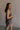Side view of female model wearing the Vera Washed Black Sleeveless Romper which features Washed Black Cotton Fabric, Two Side Pockets , V-Neckline, Sleeveless and Adjustable Straps