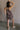 Full body back view of female model wearing the Vera Washed Black Sleeveless Romper which features Washed Black Cotton Fabric, Two Side Pockets , V-Neckline, Sleeveless and Adjustable Straps