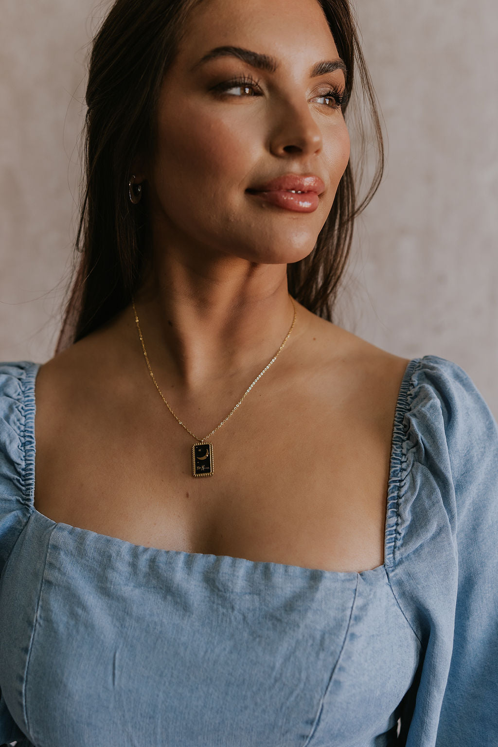 Close up view of female model wearing the Naomi Black & Gold Crescent Necklace which features adjustable gold chain layer with a gold and black rectangle medallion, gold crescent moon detail