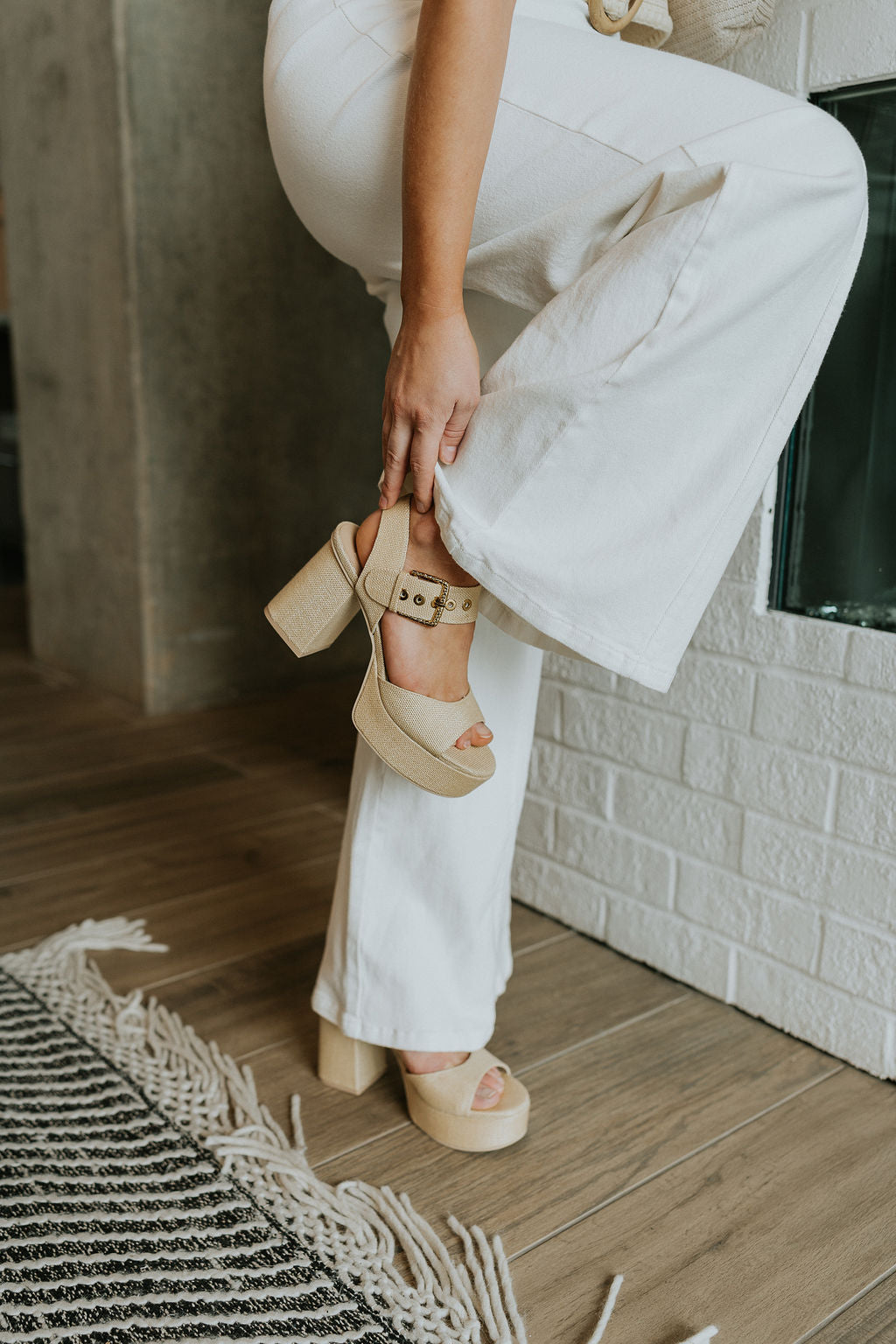 Front side view of female model wearing the Bobby Heel in Natural which features Natural Raffia Fabric, Gold Adjustable Buckle, Sturdy Ankle Strap and 4" Wrapped Heel, 1 1/4" Platform Sole