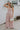 Full body view of female model wearing the Aleah Mauve Pink Sleeveless Jumpsuit which features Mauve Pink Lightweight Fabric, Wide Leg Pants, Upper Ruched Detail, Two Side Pockets, Scooped Neckline, Adjustable Straps and Open Back with Tie Closure and Zipper