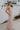 Full body side view of female model wearing the Aleah Mauve Pink Sleeveless Jumpsuit which features Mauve Pink Lightweight Fabric, Wide Leg Pants, Upper Ruched Detail, Two Side Pockets, Scooped Neckline, Adjustable Straps and Open Back with Tie Closure and Zipper