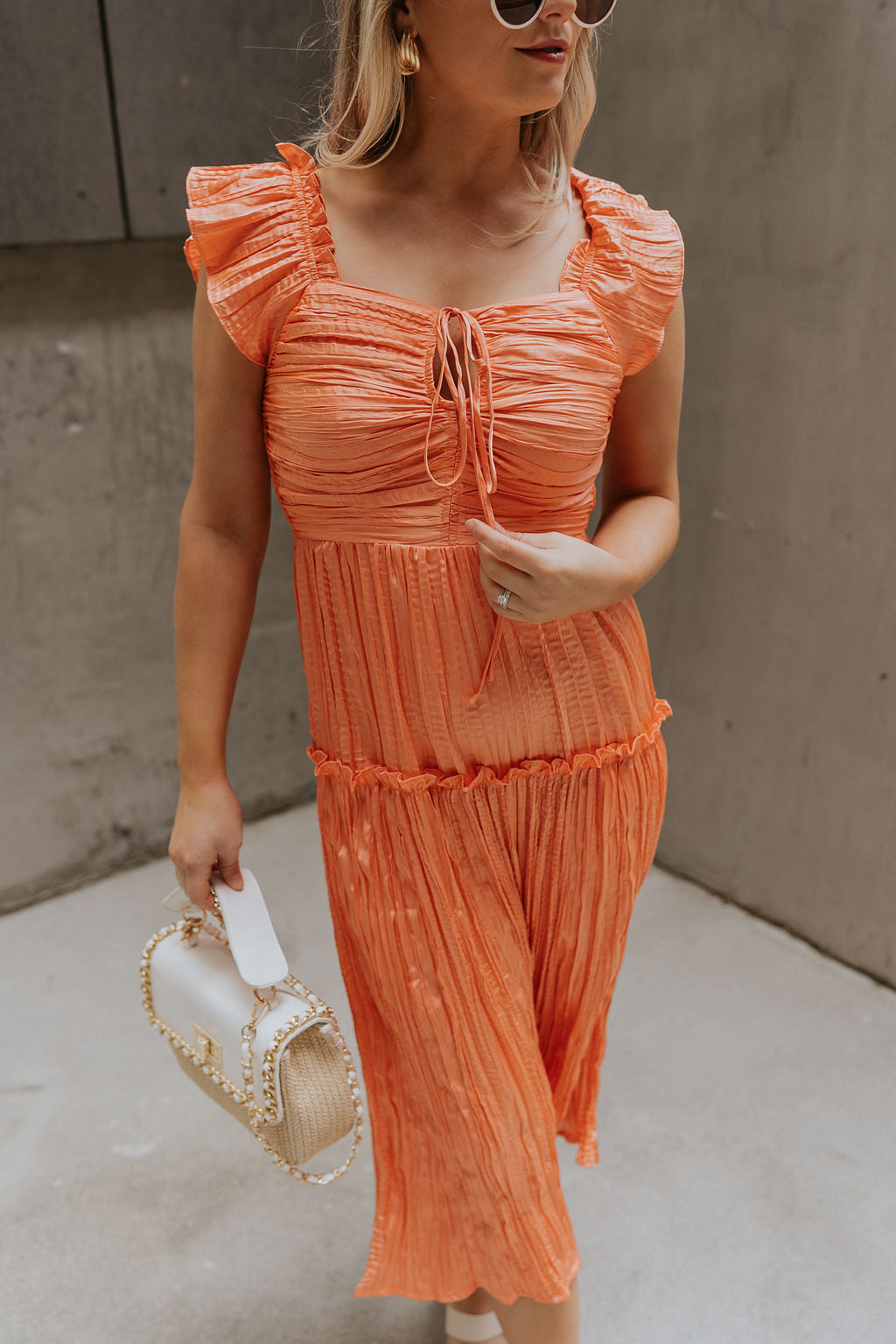 Close up view of female model wearing the Maren Peach Key Hole Midi Dress which features Peach Crinkle Fabric, Midi Length, Peach Lining, Square Neckline with Key Hole Tie Closure, Ruffle Straps andTier Ruffle Skirt Detail