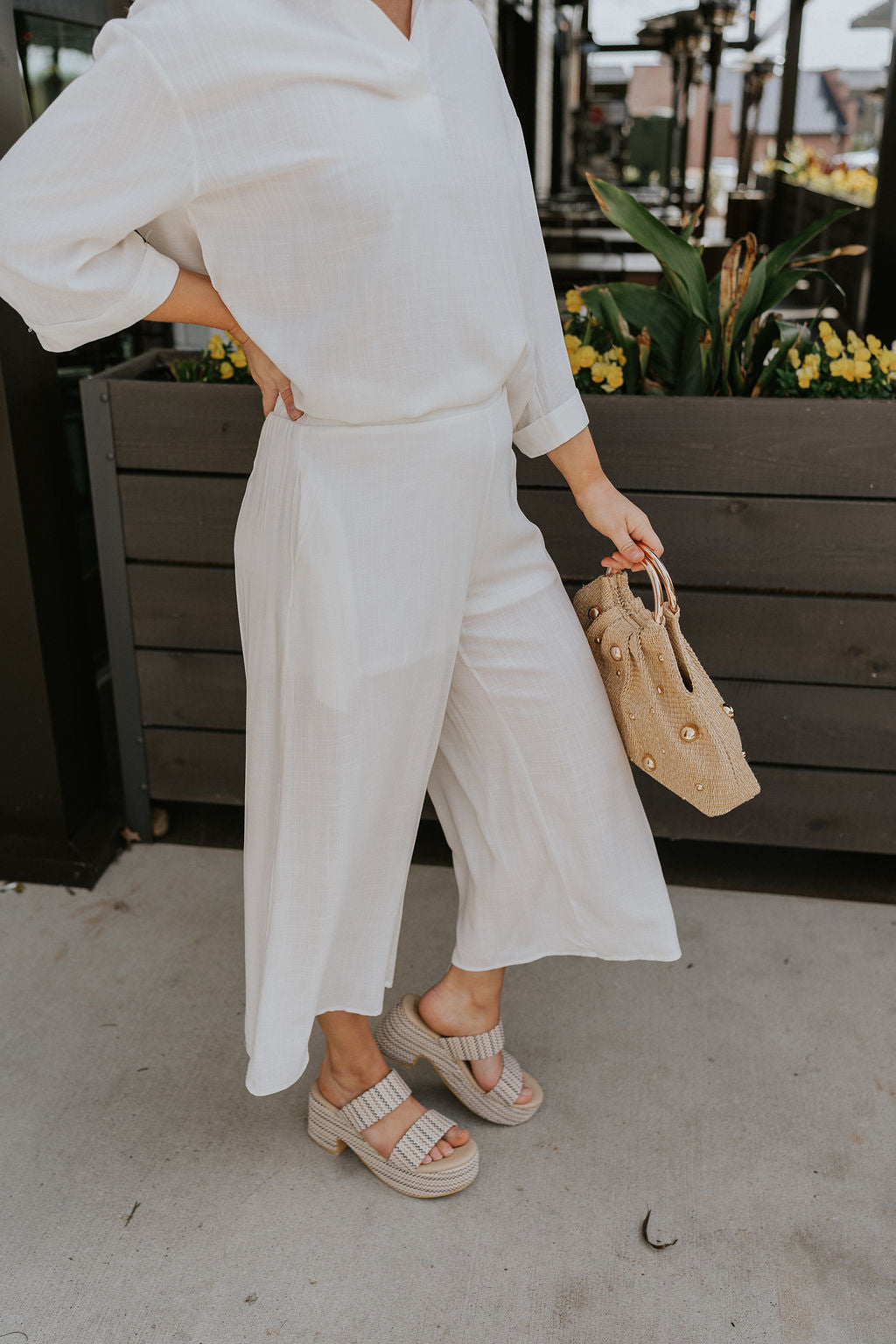 Side view of female model wearing the Rebecca Ivory Linen Cropped Pants which features Ivory Linen Fabric, Cropped Pant Legs, Ivory Lining, Two Side Pockets and Elastic Waistband
