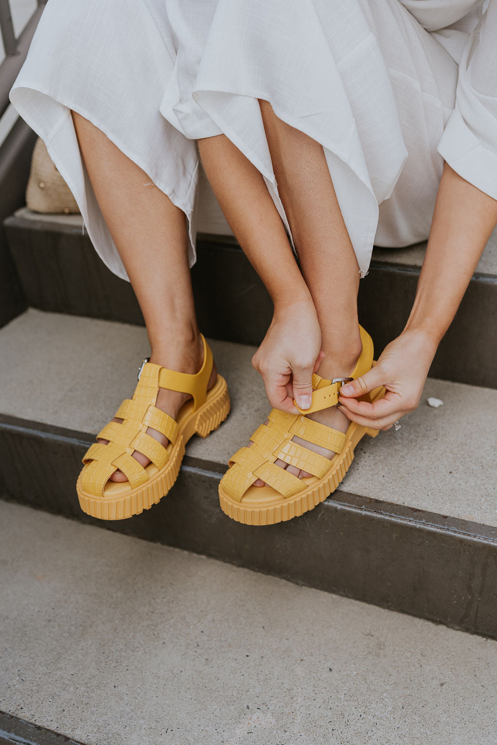 Side view of female model wearing the ONA Streetworks Fisherman Sandal in Yellow Ray & Pilsner which features Yellow Leather Upper Fabric, Monochrome Croc Details, Fisherman Sandal Silhouette, Adjustable Buckle Closure, 2" Heel Height and 1 1/2" Platform Height