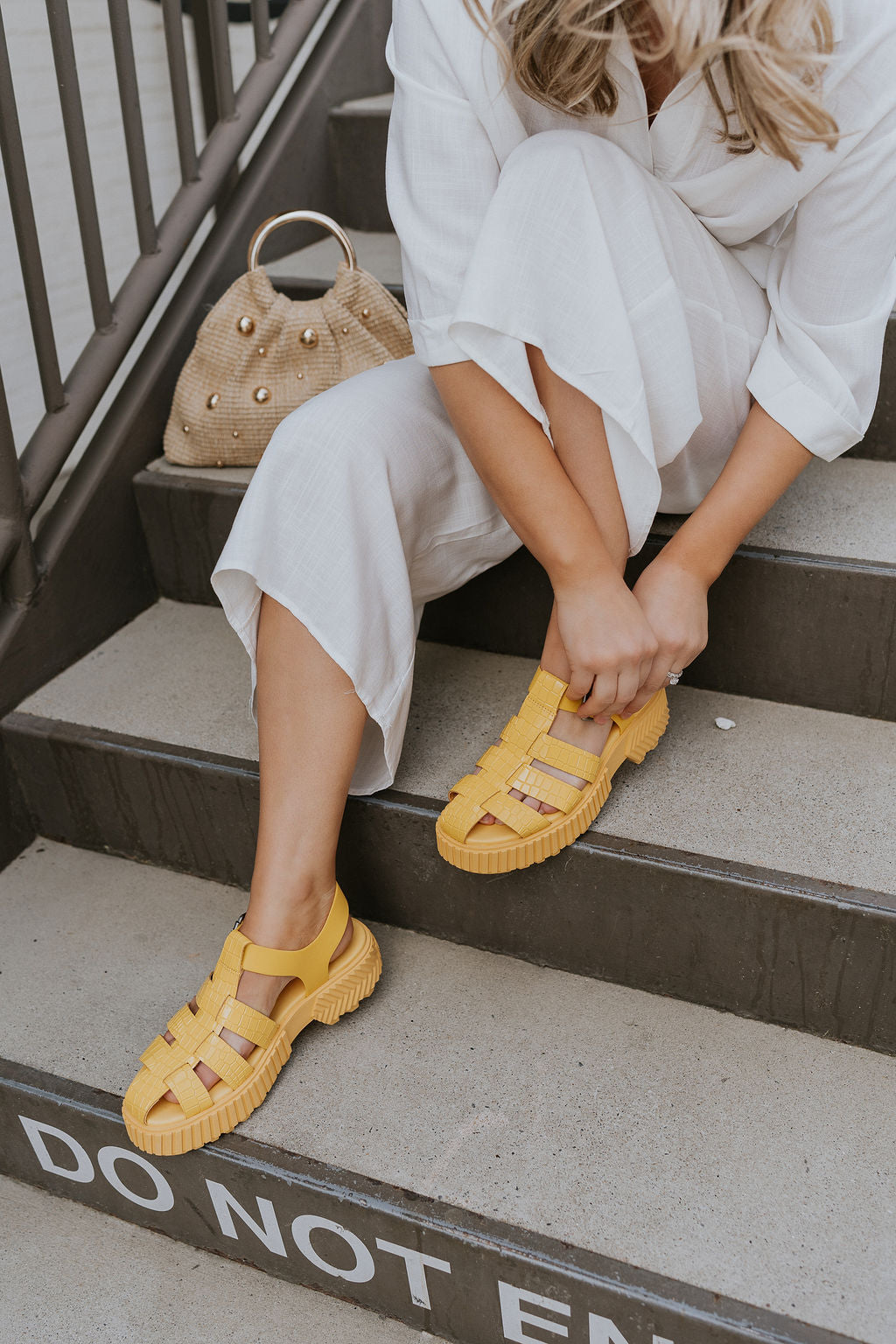 Side view of female model wearing the ONA Streetworks Fisherman Sandal in Yellow Ray & Pilsner which features Yellow Leather Upper Fabric, Monochrome Croc Details, Fisherman Sandal Silhouette, Adjustable Buckle Closure, 2" Heel Height and 1 1/2" Platform Height