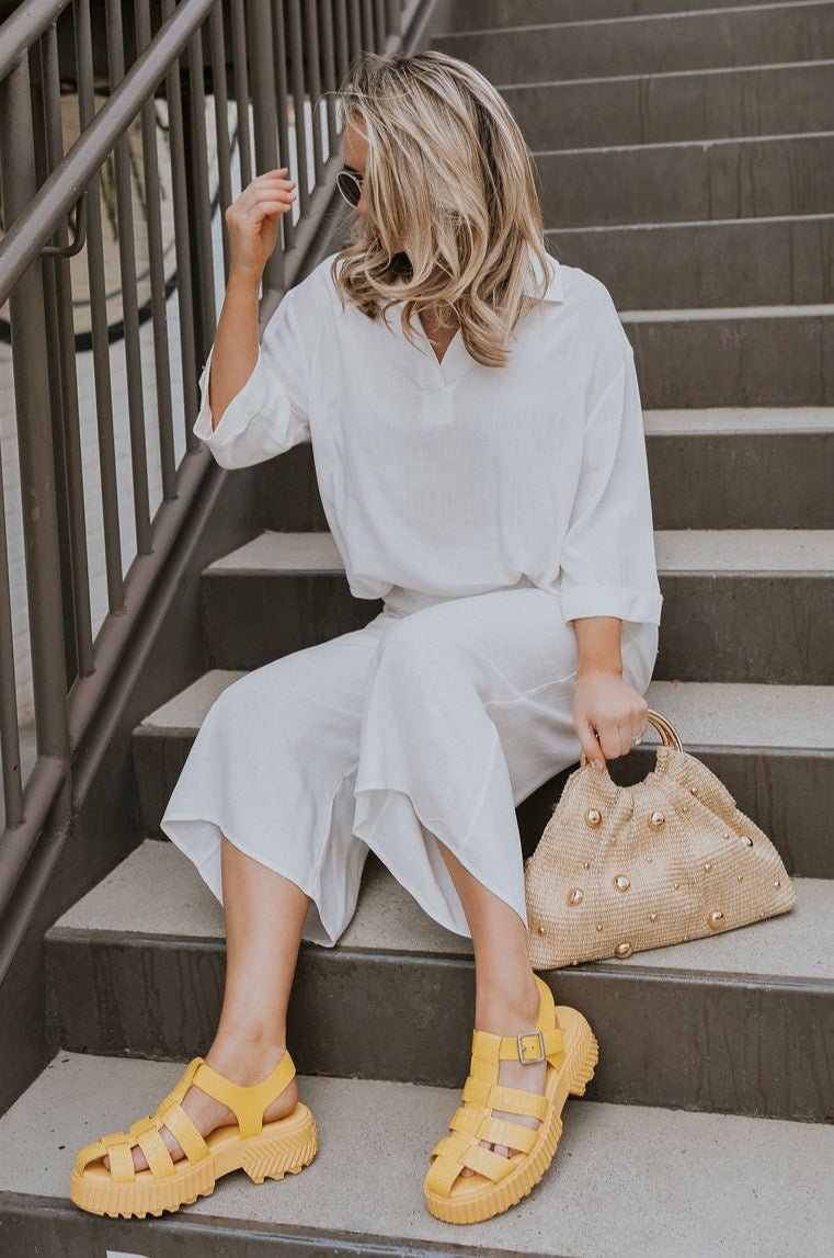 Full body view of female model wearing the ONA Streetworks Fisherman Sandal in Yellow Ray & Pilsner which features Yellow Leather Upper Fabric, Monochrome Croc Details, Fisherman Sandal Silhouette, Adjustable Buckle Closure, 2" Heel Height and 1 1/2" Platform Height