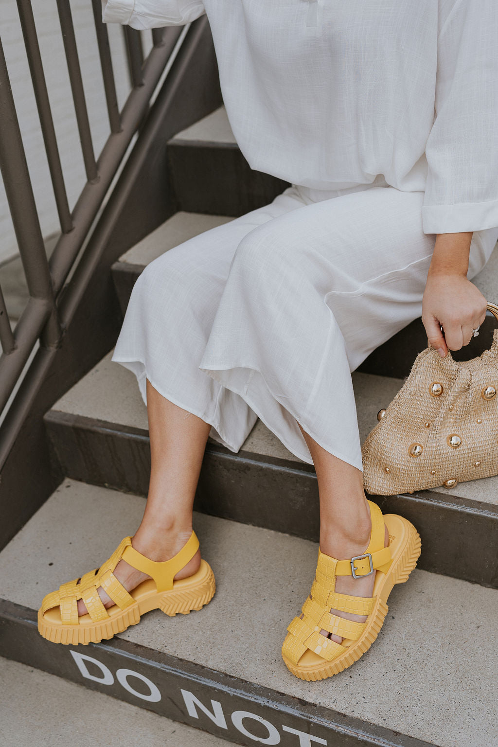 Side view of female model wearing the ONA Streetworks Fisherman Sandal in Yellow Ray & Pilsner which features Yellow Leather Upper Fabric, Monochrome Croc Details, Fisherman Sandal Silhouette, Adjustable Buckle Closure,  2" Heel Height and 1 1/2" Platform Height