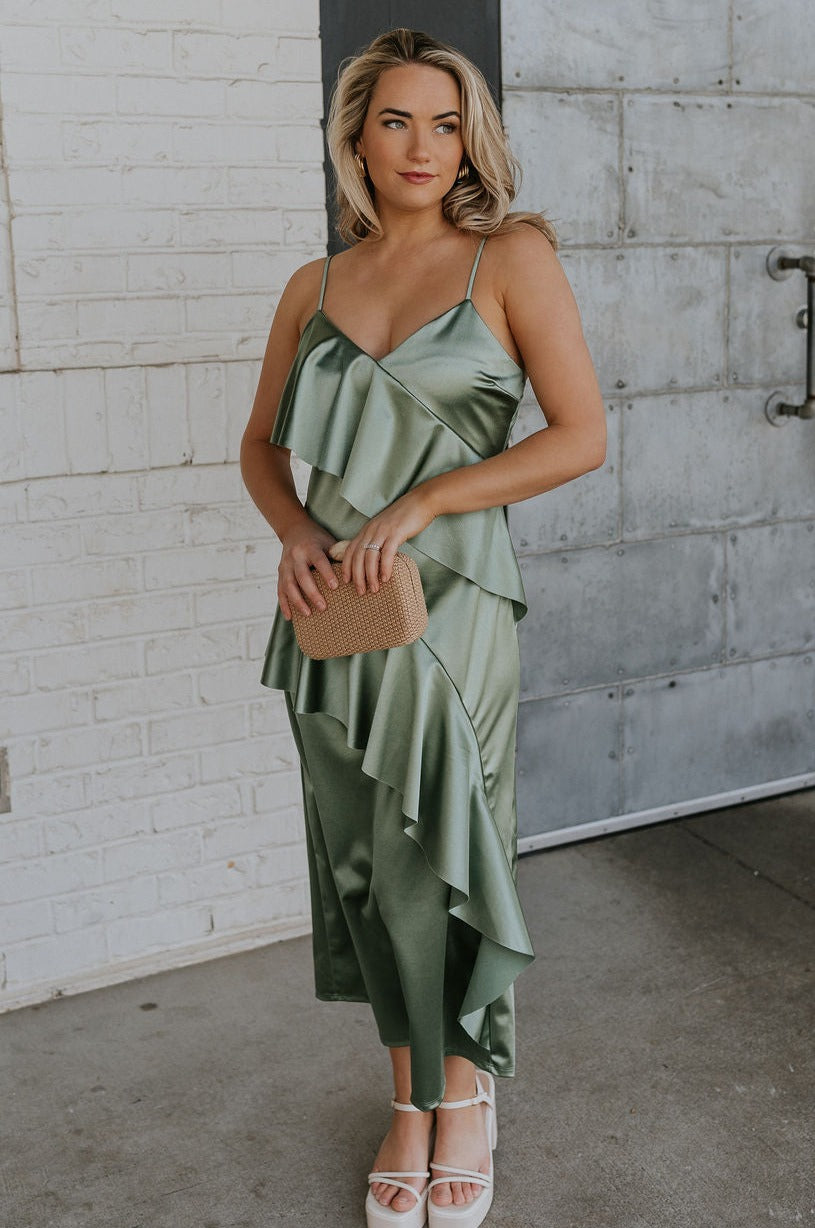 Full body view of female model wearing the Azalea Dark Sage Satin Ruffle Midi Dress which features Green satin fabric Diagonal ruffles down the bust and waist, Spaghetti straps, V-Neckline, Elastic across the back top and Midi length