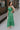 Full body side view of female model wearing the Selah Green Smocked Midi Dress which features Green Lightweight Fabric, Ruffle Tiered Body, Green Lining, Midi Length, Smocked Upper, Square Neckline and Thick Straps