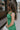 Side view of female model wearing the Selah Green Smocked Midi Dress which features Green Lightweight Fabric, Ruffle Tiered Body, Green Lining, Midi Length, Smocked Upper, Square Neckline and Thick Straps