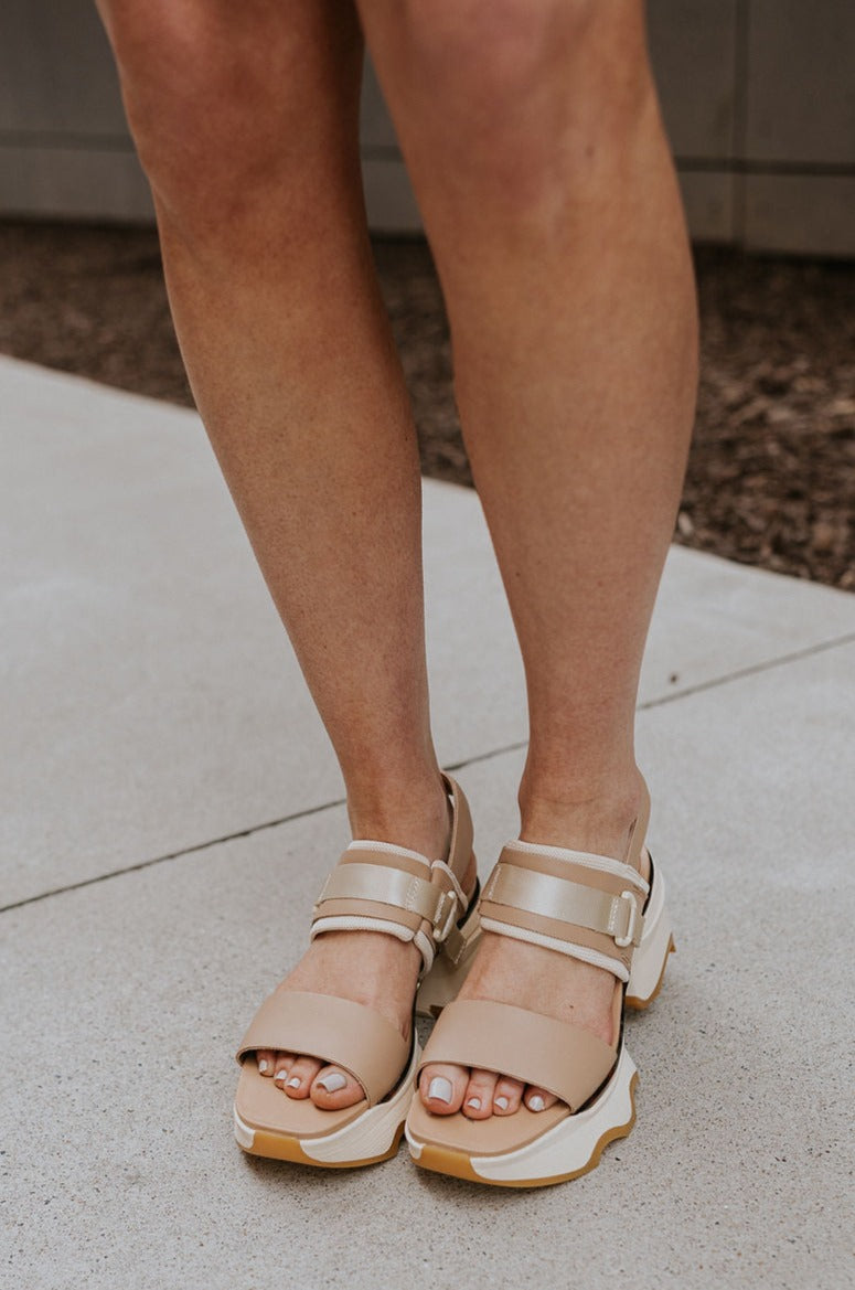 Front view of female model wearing the Kinetic Impact Slingback Heel in Honest Beige & Honest White which features Beige and Cream Leather Upper Fabric, Leather Strap, Adjustable Hook and Velcro Strap Closure, 1 1/2" Platform Sole, 2 1/12" Heel Height and Tortoise Sole Lining Details