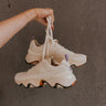 Front side view of female model holding the Kinetic Impact II Wonder Lace Sneaker in Honey White & Euphoric Lilac which features Light Beige Mesh Fabric & Suede/Leather Upper, Tortoise Detail Rubber Sole, Lace Up Details and Lavender Pull Tab .