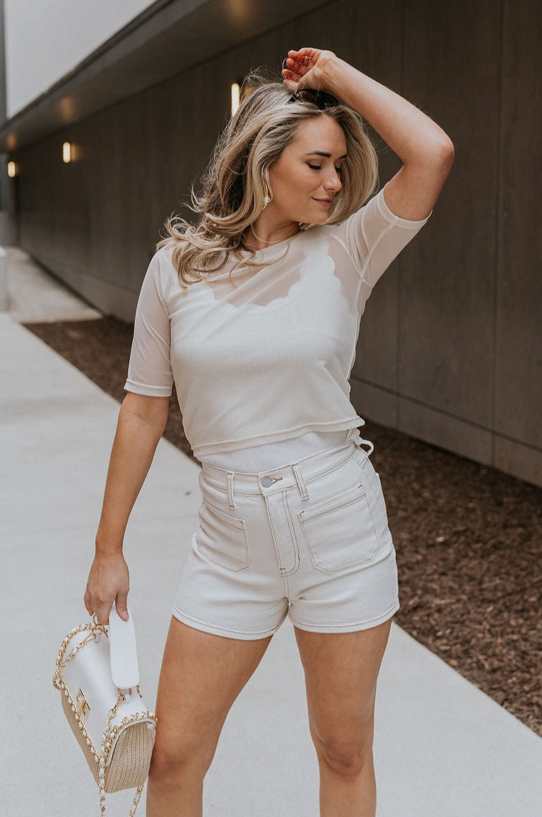 Front view of female model wearing the Lola Cream Sheer Short Sleeve Top which features Cream Sheer Fabric, Round Neckline, Cropped Waist and Short Sleeves