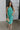 Full body view of female model wearing the Vera Halter Cross Neckline Midi Dress in Green which features Lightweight Fabric, Lining, Midi Length, Side Ties Waistband, Halter Cross Neckline, Adjustable Straps and  Sleeveless. 