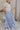 Side view of female model wearing the Alana Periwinkle Tiered Maxi Skirt which features Periwinkle Lightweight Fabric, Maxi Length, Periwinkle Thigh Length Lining, Tiered Body and Elastic Waistband with Drawstring Ties